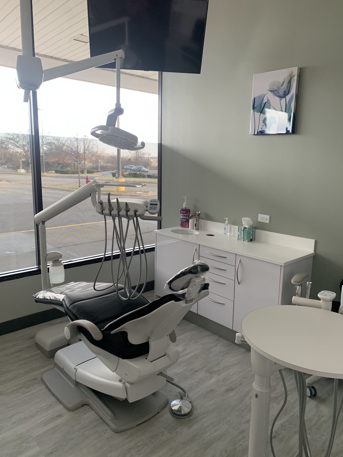 Best Dental Spa treatment room with a dental chair, overhead light, and a ceiling television
