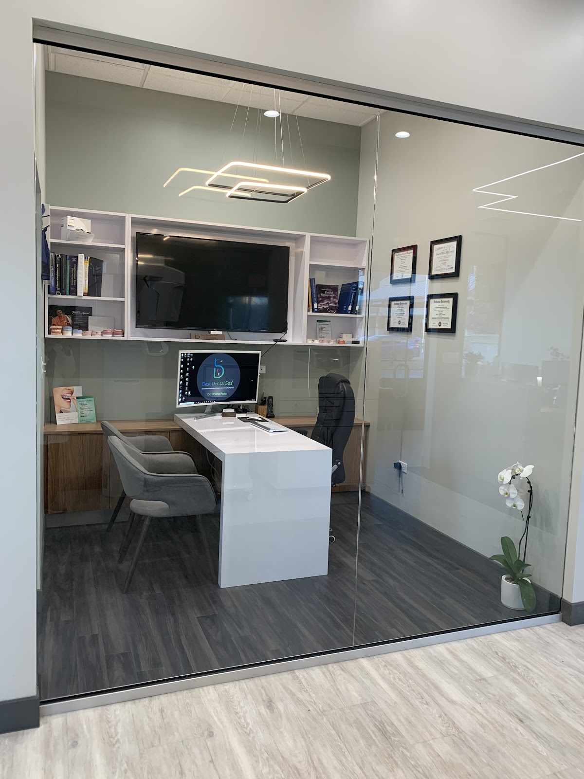 Private consultation room at Best Dental Spa with a desk, two armchairs, and framed credentials